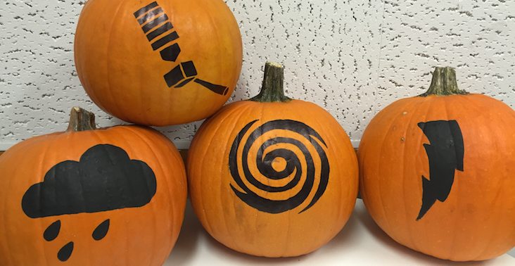 Four pumpkins painted with different images, including a weather satellite, raincloud, hurricane and lightning bolt.